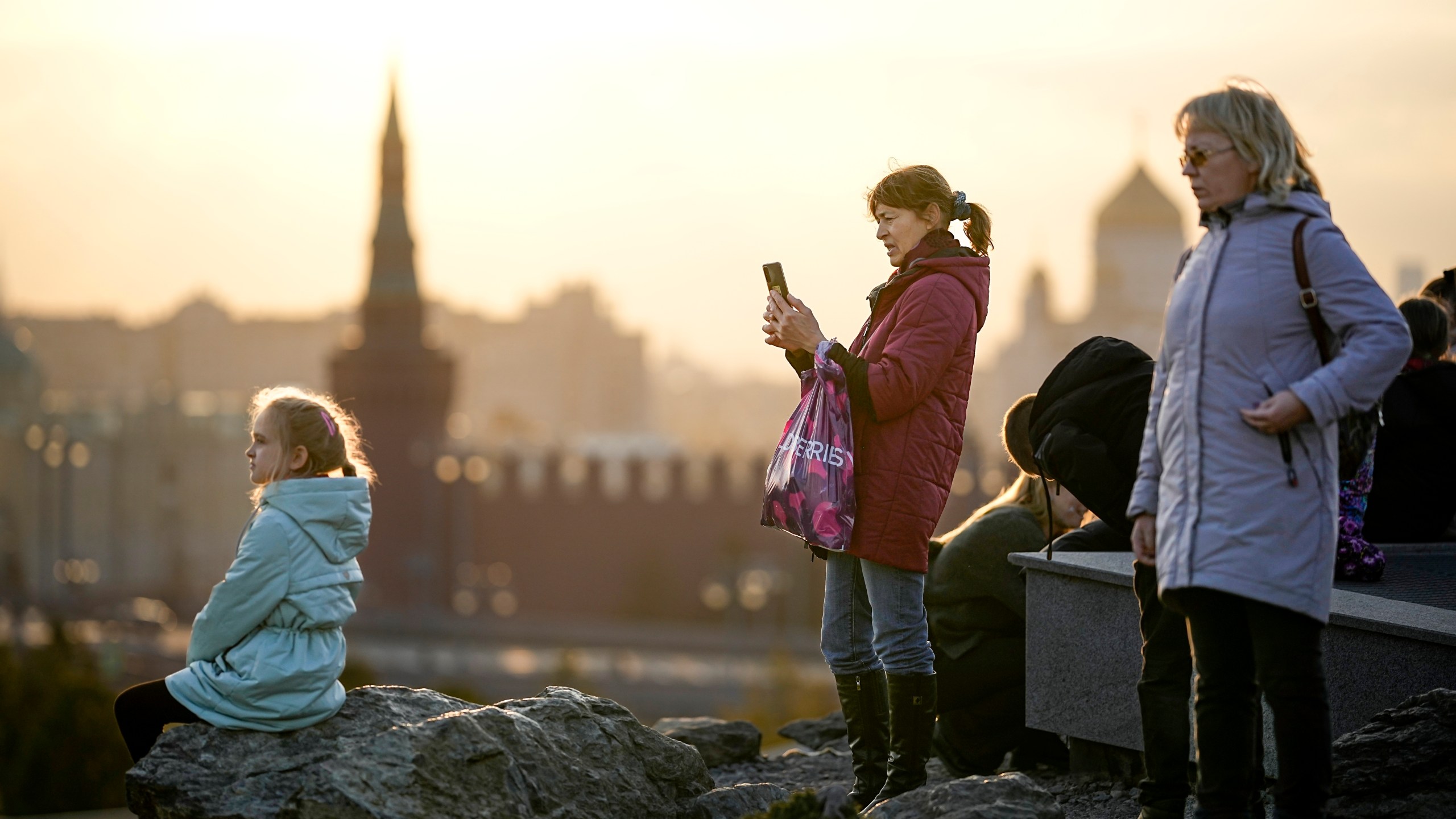 People enjoy a warm autumn sunset at Zaryadye Park near Red Square with the Kremlin in the background in Moscow, Russia, on Wednesday, Nov. 1, 2023. The temperature in Moscow rose to 14 degrees Celsius (57,2 Fahrenheit) and broke the 1934 record by 1.5 degrees Celsius, which is unusual for the beginning of November. (AP Photo/Alexander Zemlianichenko)